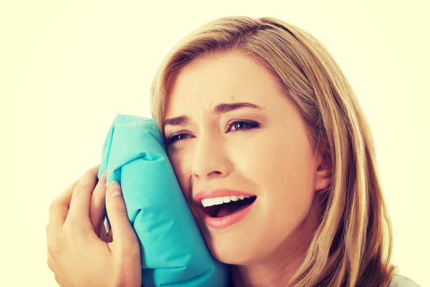 Woman heaving tooth ache, holding ice bag