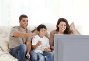 Family laughing while watching television together